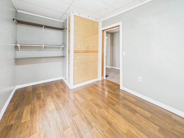 unfurnished bedroom featuring a closet, baseboards, a drop ceiling, and wood finished floors