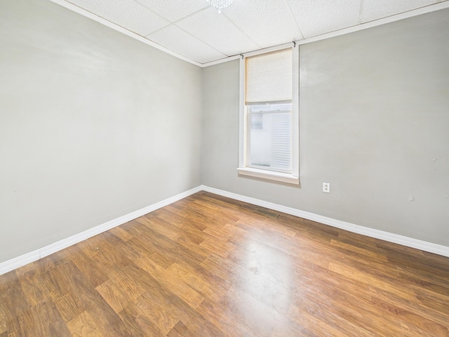 spare room featuring wood finished floors, baseboards, and a drop ceiling