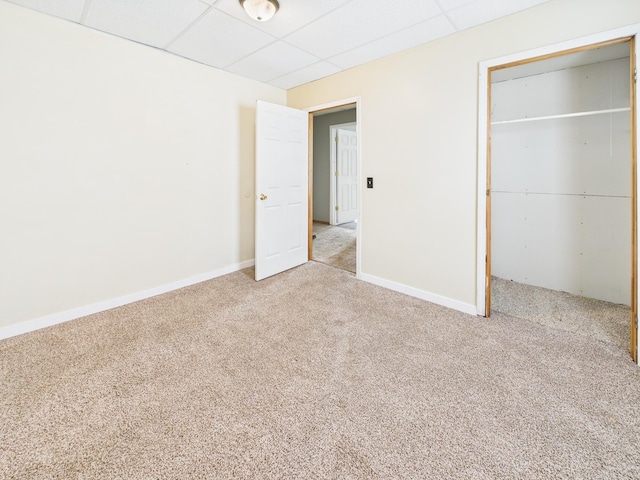 unfurnished bedroom with a closet, baseboards, a paneled ceiling, and carpet