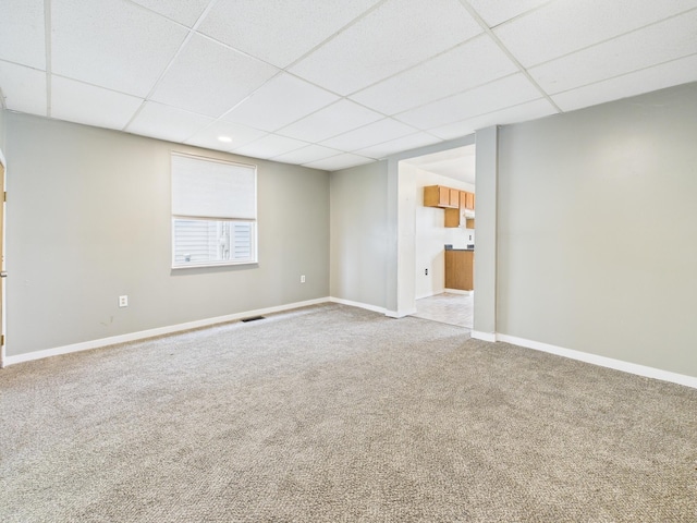 empty room with visible vents, baseboards, a drop ceiling, and carpet