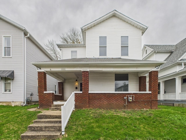 view of front facade with a front yard, brick siding, and covered porch