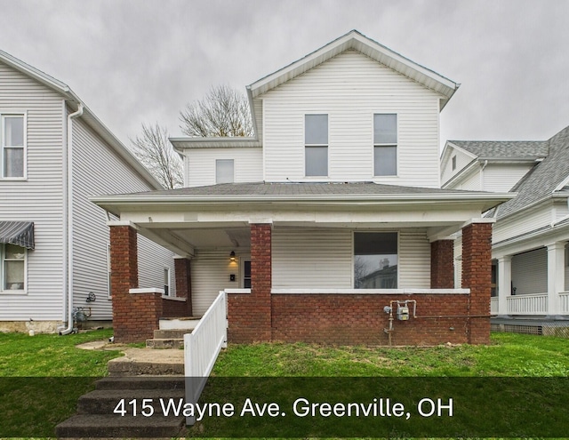 view of front of house featuring a porch, a front yard, and brick siding