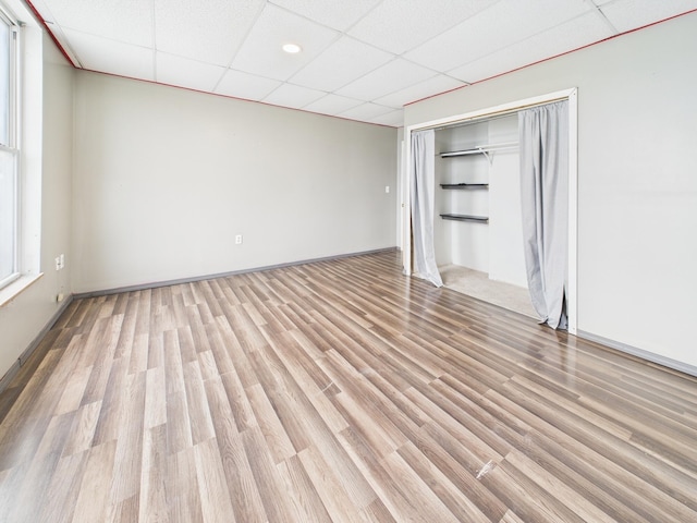 unfurnished bedroom featuring light wood-type flooring, a closet, and a drop ceiling