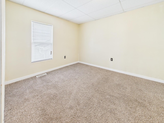 carpeted empty room with baseboards, a drop ceiling, and visible vents