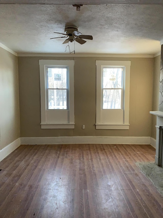 spare room featuring a textured ceiling, wood-type flooring, and a healthy amount of sunlight