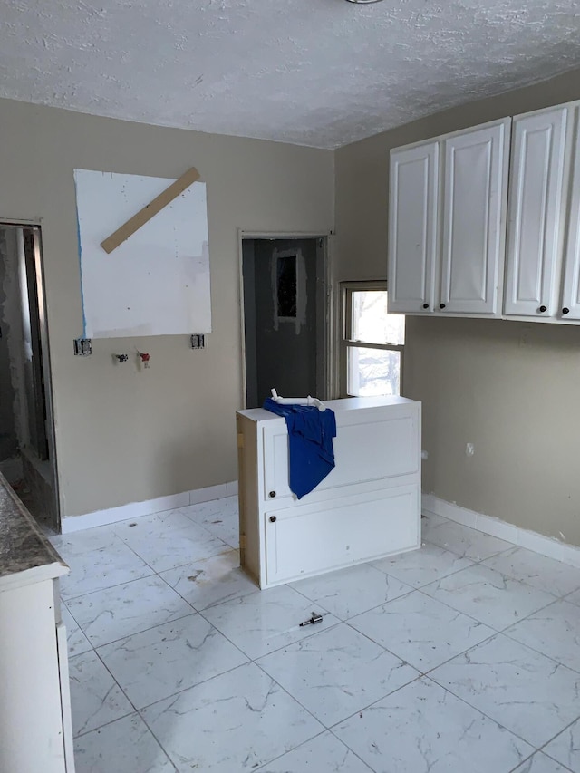 kitchen featuring a textured ceiling and white cabinets