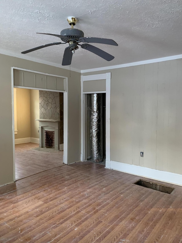 unfurnished living room featuring hardwood / wood-style flooring, ornamental molding, and a textured ceiling