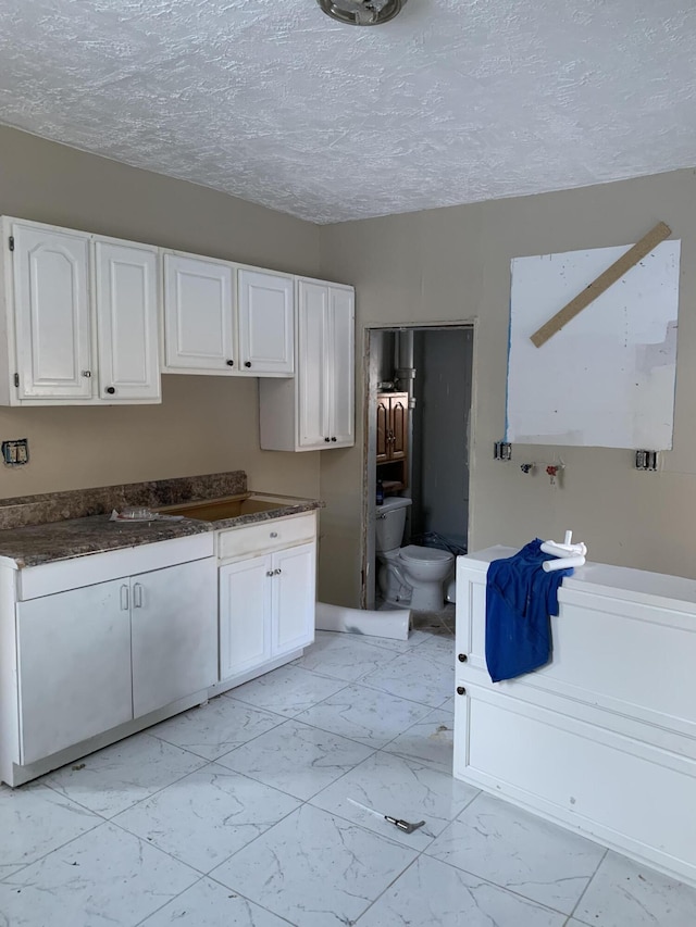 kitchen with a textured ceiling and white cabinets