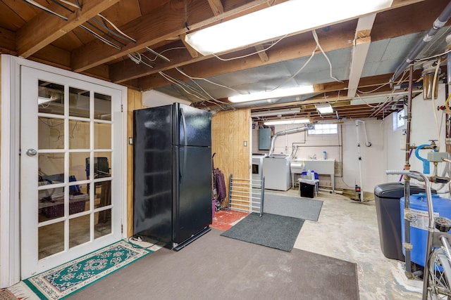 basement featuring black fridge, washer / clothes dryer, electric panel, and sink