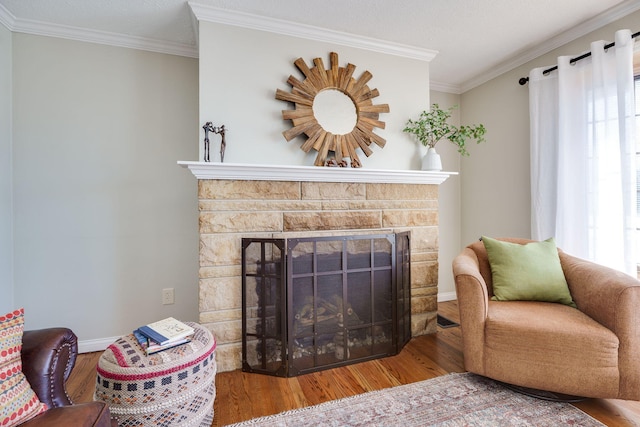 living room featuring crown molding, hardwood / wood-style flooring, and a stone fireplace