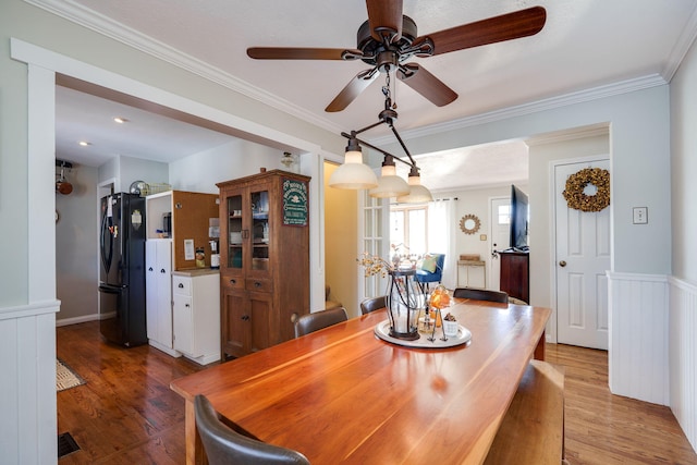 dining space with hardwood / wood-style flooring, crown molding, and ceiling fan