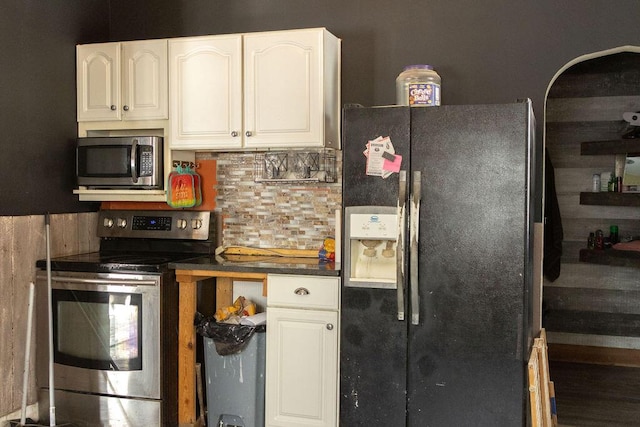 kitchen featuring backsplash, wooden walls, white cabinets, and appliances with stainless steel finishes