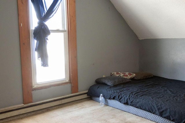 carpeted bedroom featuring lofted ceiling and a baseboard heating unit