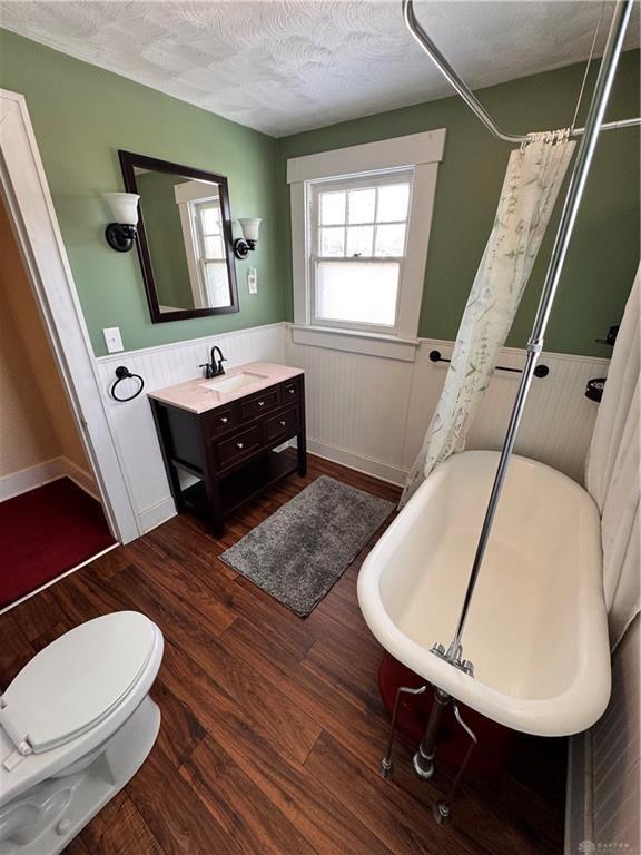 230 New Columbia Blvd, Sidney, OH 45365 - full bathroom with vanity, a shower with curtain, wood finished floors, a textured ceiling, and wainscoting