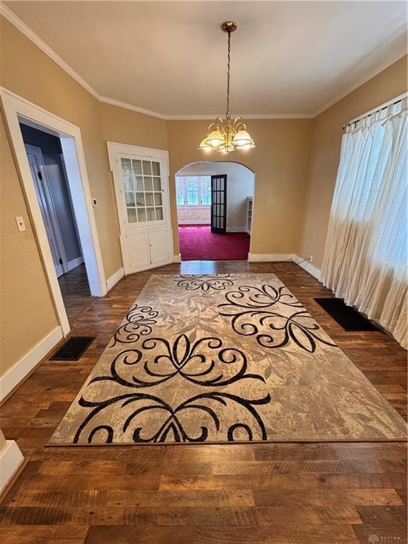 230 New Columbia Blvd, Sidney, OH 45365 - unfurnished dining area featuring dark wood finished floors, baseboards, visible vents, arched walkways, and ornamental molding