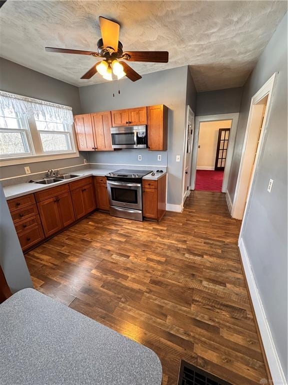 230 New Columbia Blvd, Sidney, OH 45365 - kitchen featuring ceiling fan, brown cabinets, stainless steel appliances, a sink, and dark wood-style floors