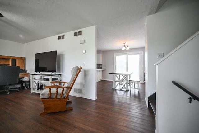 living room with visible vents, a textured ceiling, and wood finished floors