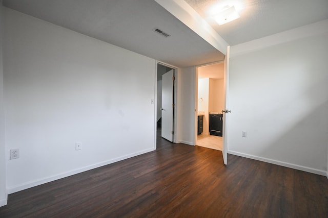 unfurnished room with visible vents, baseboards, and dark wood-type flooring