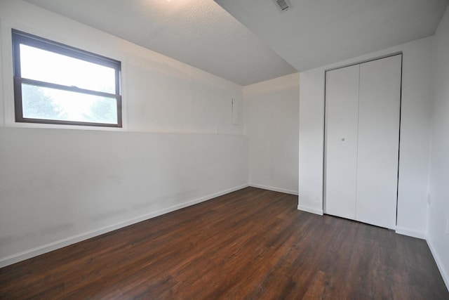 unfurnished bedroom featuring dark wood-style flooring, baseboards, visible vents, and a closet