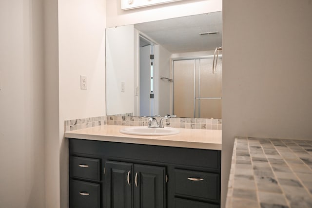 full bath with vanity, a shower with shower door, and visible vents