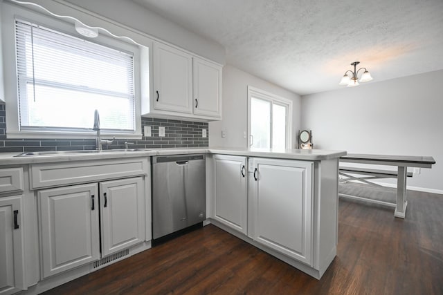 kitchen with a sink, dishwasher, a peninsula, backsplash, and visible vents