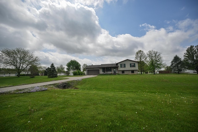 split level home featuring an attached garage, concrete driveway, and a front yard