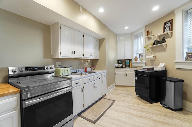 kitchen with sink, stainless steel electric range, white cabinets, and light wood-type flooring