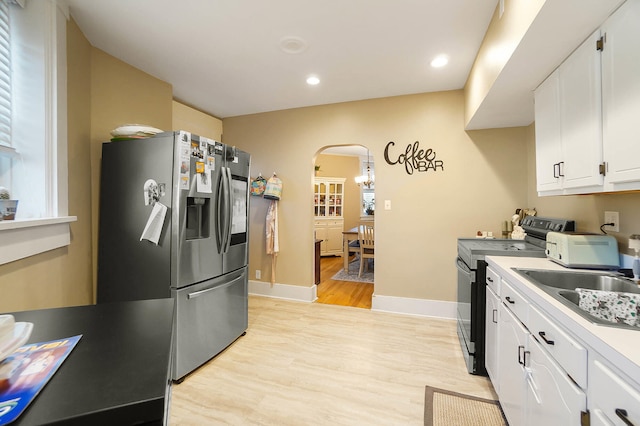 kitchen featuring sink, white cabinetry, stainless steel refrigerator with ice dispenser, light hardwood / wood-style floors, and black range with electric cooktop