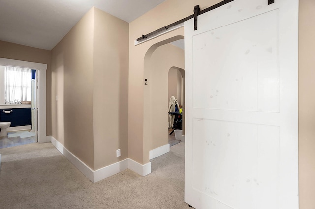 hallway featuring a barn door and light carpet