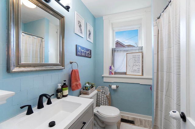 bathroom featuring vanity, toilet, and tile walls