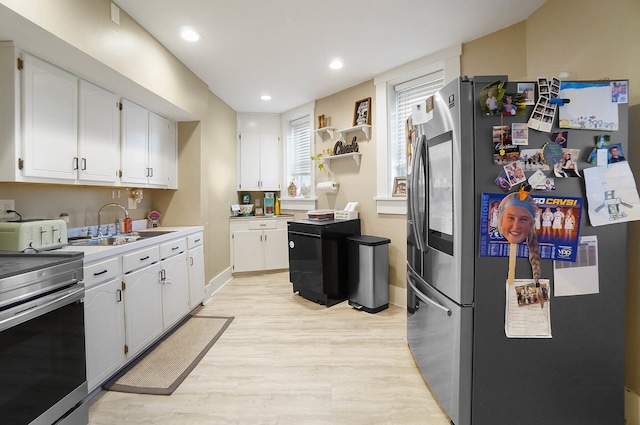 kitchen with appliances with stainless steel finishes, light hardwood / wood-style floors, sink, and white cabinets