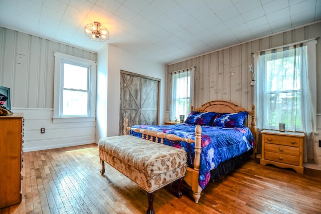 bedroom featuring wooden walls, baseboards, and wood-type flooring