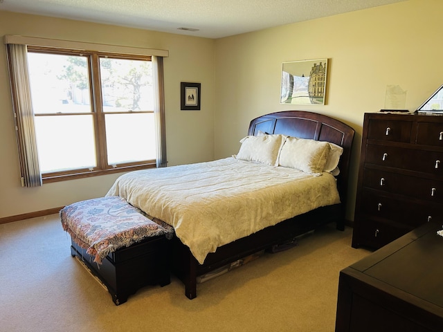 bedroom featuring visible vents, light colored carpet, a textured ceiling, and baseboards