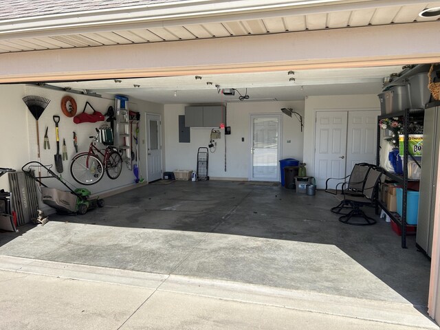 garage with electric panel, a garage door opener, and driveway