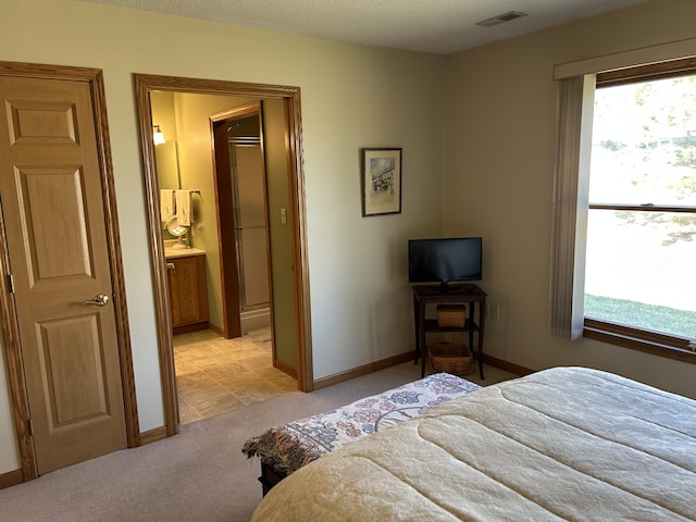 bedroom featuring a textured ceiling, baseboards, visible vents, and light carpet