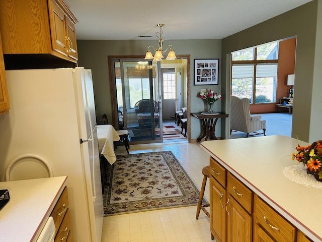 kitchen with plenty of natural light, freestanding refrigerator, brown cabinetry, and light countertops