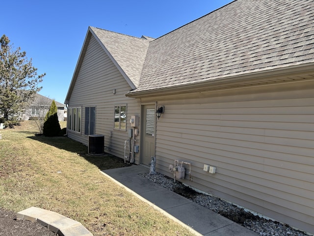 view of home's exterior with a yard, roof with shingles, and central AC
