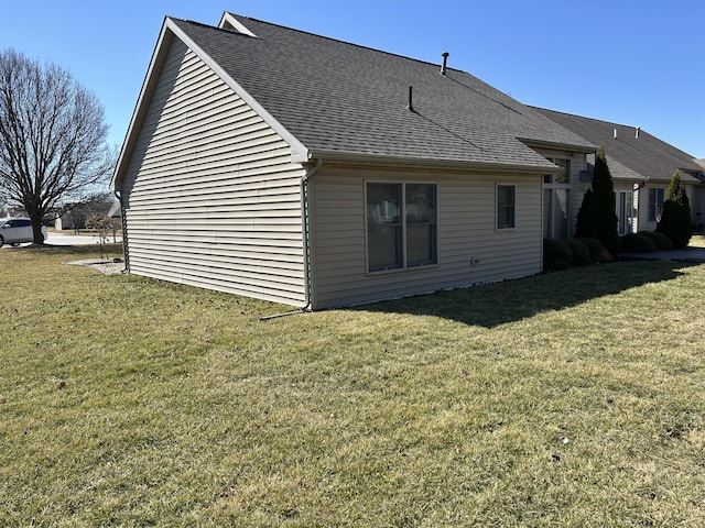 back of property with a lawn and roof with shingles