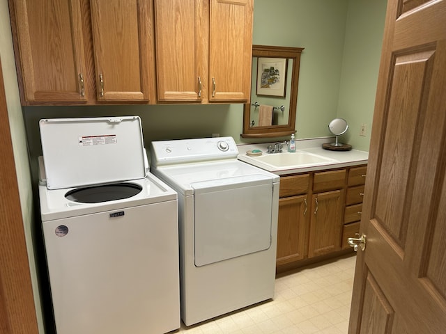 laundry room featuring washer and clothes dryer, cabinet space, light floors, and a sink