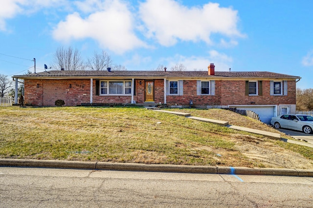 ranch-style house with brick siding, an attached garage, a chimney, and a front lawn