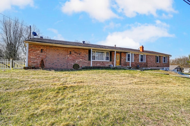 view of front of property with brick siding, a chimney, a front yard, and fence