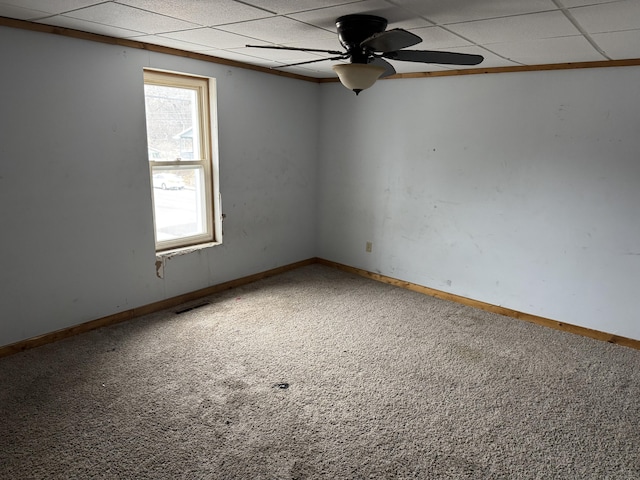 empty room with a paneled ceiling, ceiling fan, and carpet flooring