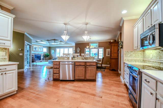 1205 Daylily Way, Troy, OH 45373 - kitchen with stainless steel appliances, crown molding, open floor plan, light countertops, and decorative light fixtures
