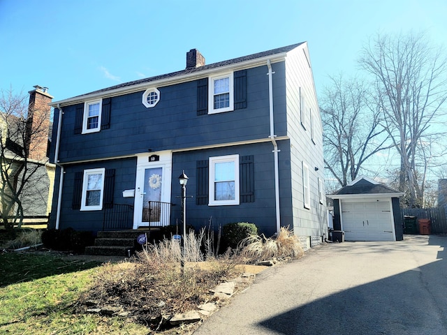 colonial home featuring an outbuilding, driveway, fence, a garage, and a chimney