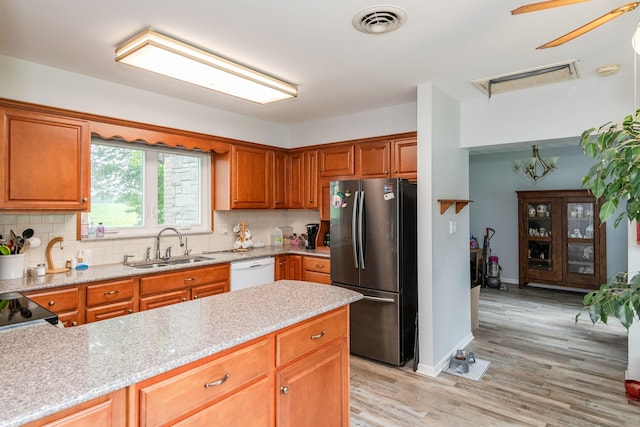 kitchen featuring a sink, visible vents, freestanding refrigerator, decorative backsplash, and dishwasher