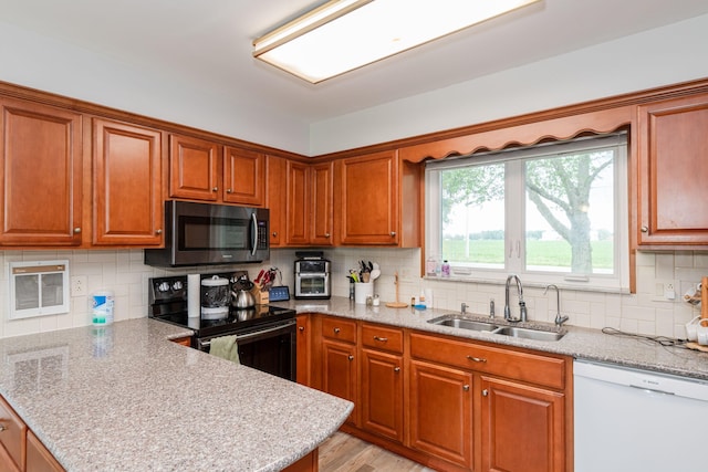 kitchen featuring stainless steel microwave, black range with electric stovetop, a peninsula, white dishwasher, and a sink