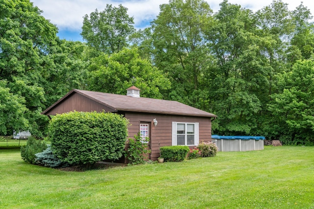 view of side of home with a covered pool and a yard