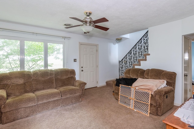 living room with visible vents, a ceiling fan, stairs, a textured ceiling, and carpet floors