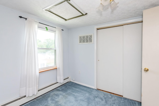 unfurnished bedroom with a baseboard radiator, carpet flooring, visible vents, a closet, and attic access