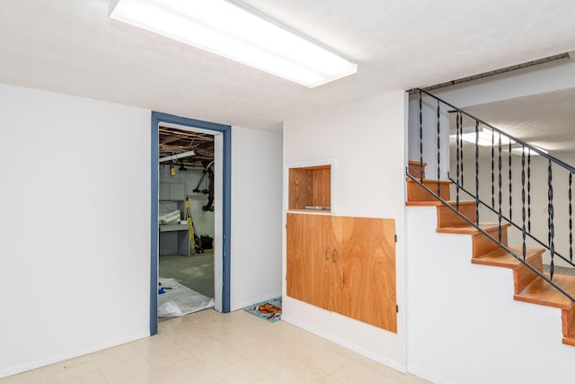 empty room featuring stairway and tile patterned floors